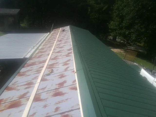 Old rusted panels beside newly installed green metal roofing — Wind Damage Roof Repair by Roofing Brothers in Sayre