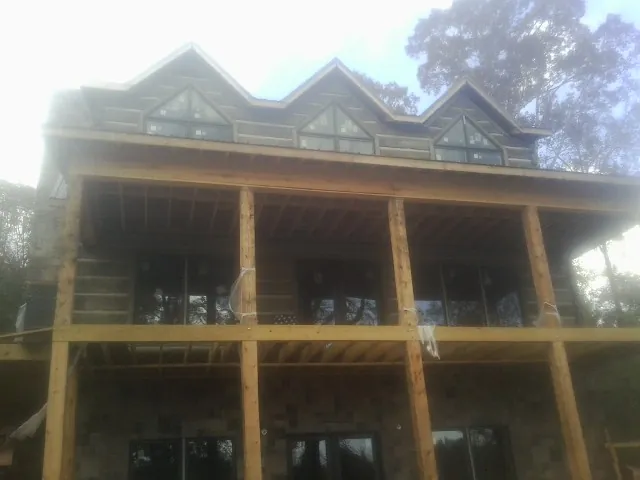 Dormers and porch framing on a large log home under construction — Roof Coating work by our crew in Sayre
