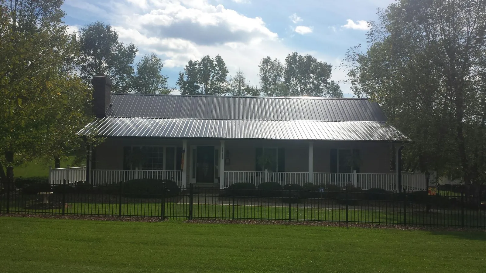 Gray metal roof on a brick ranch with a full width front porch — Gutter Guard Installation work by our crew in Sayre