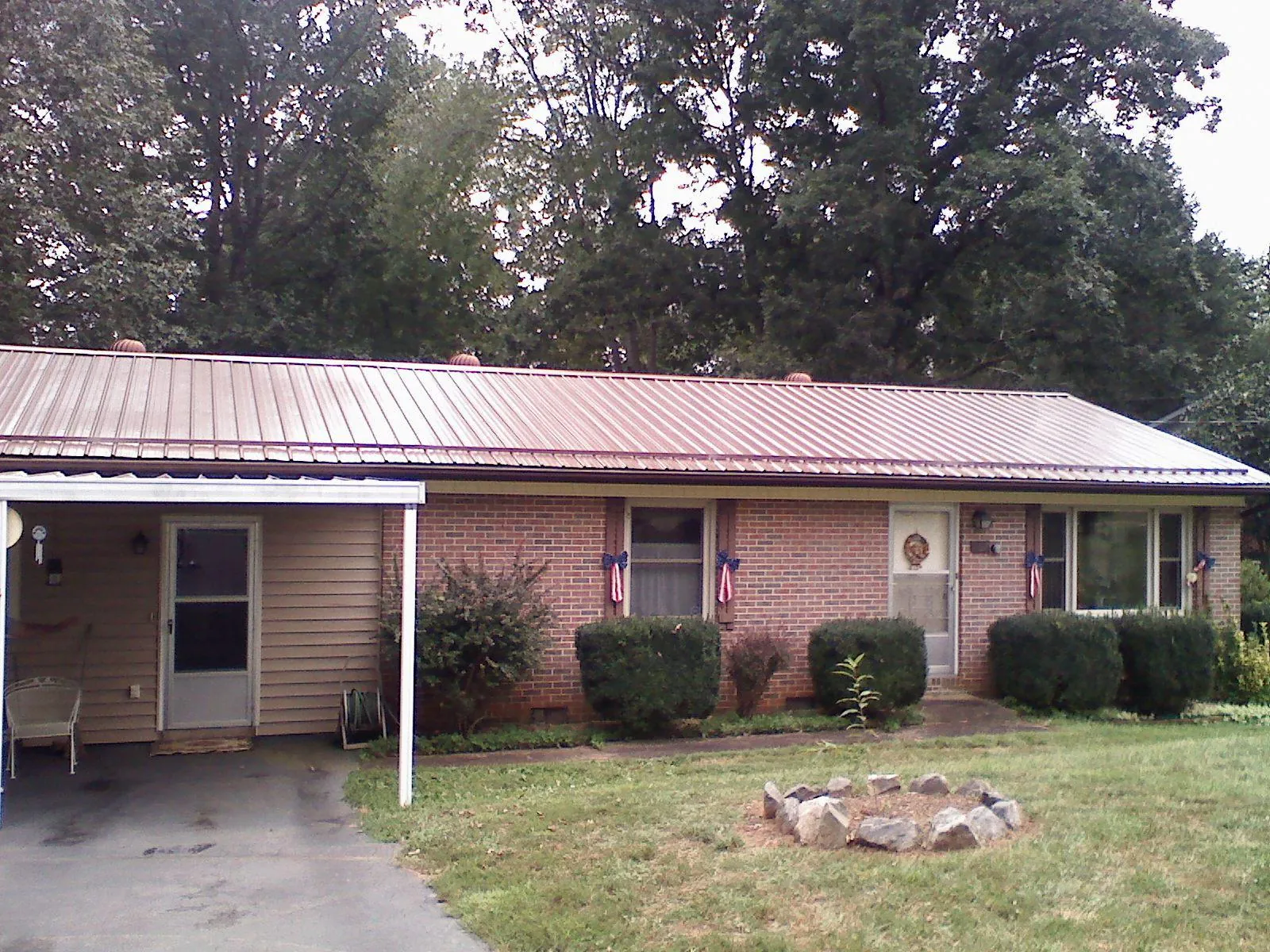 Bronze metal roof and carport on a brick ranch home — Roof Repair work by our crew in Sayre